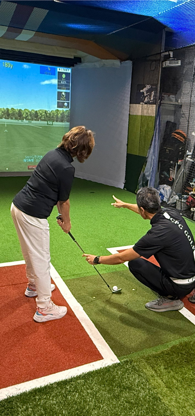 シミュレーターの前でゴルフスイングの指導を受ける様子