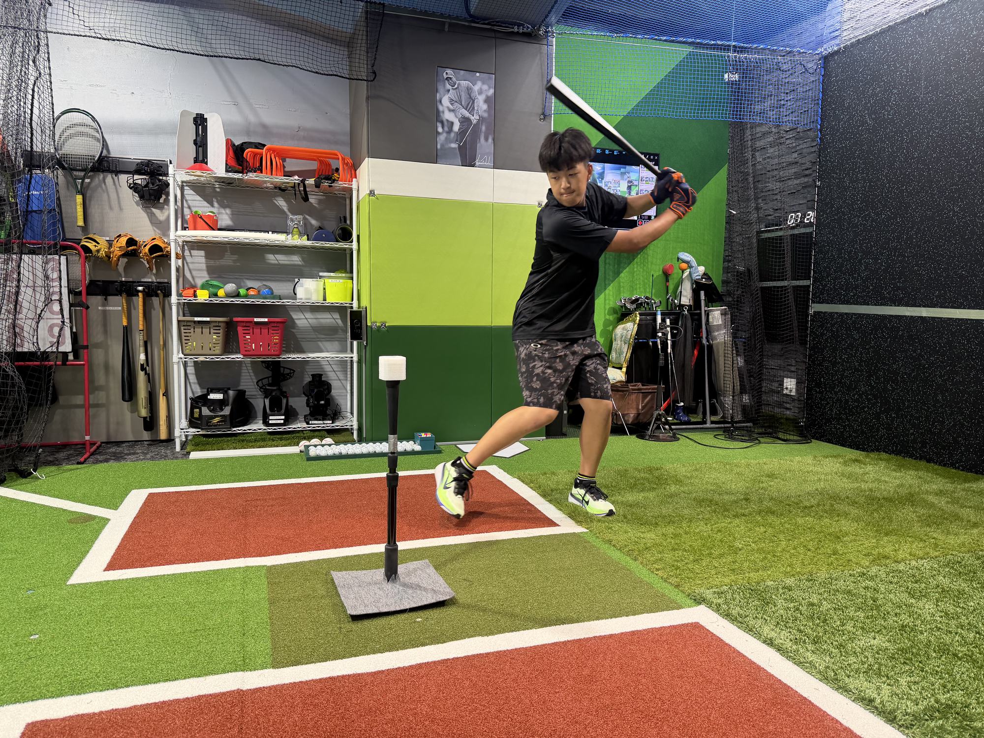 野球・ゴルフ 新宿BASE の屋内施設でティーバッティングの構えをとる選手