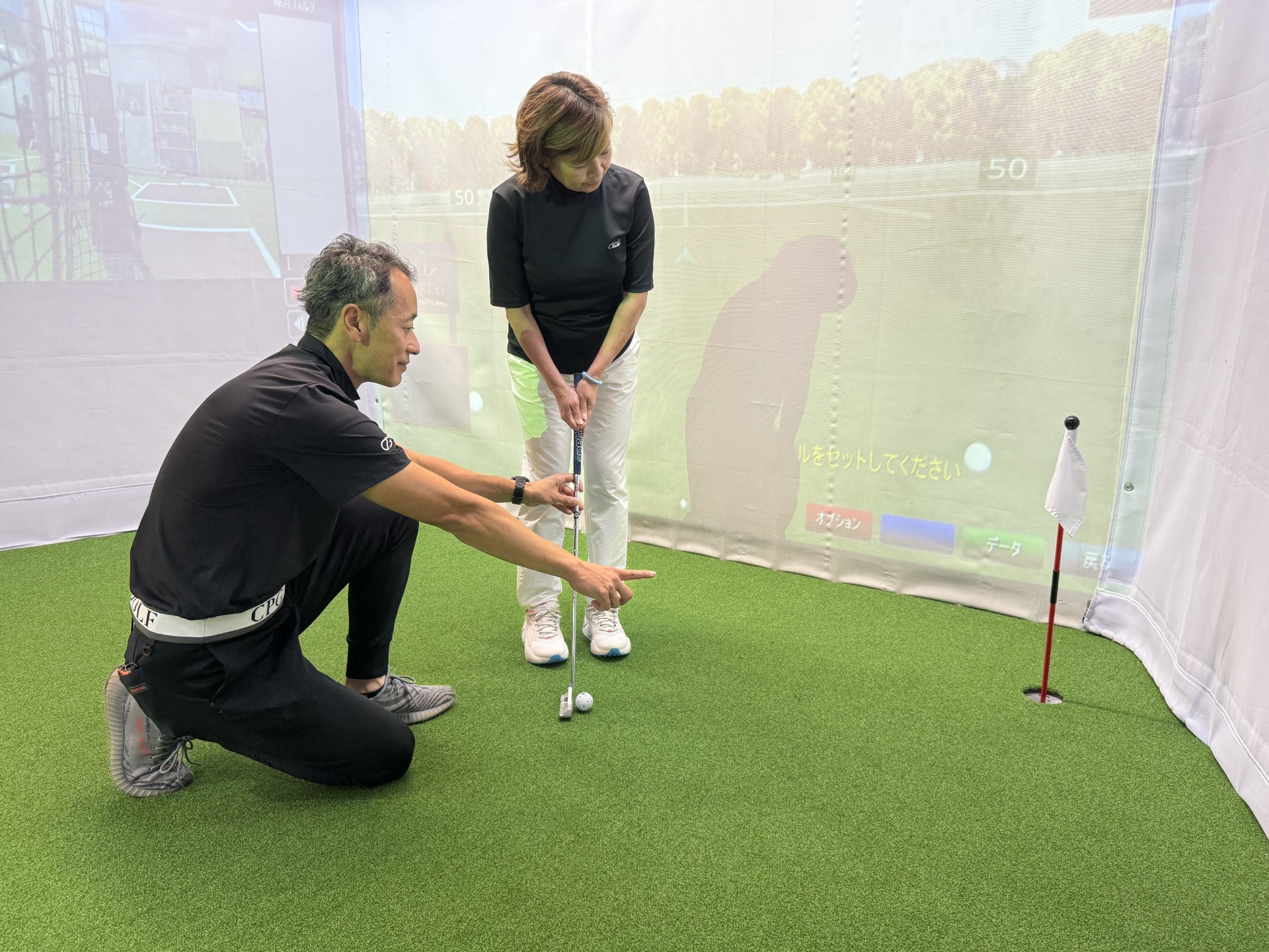 ゴルフコーチがパッティングの構えと方向を指導する様子